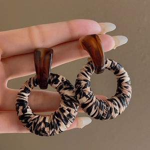 Close-up of leopard print hoop earrings with amber resin geometric studs in vintage style