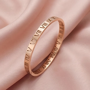 Vue détaillée du bracelet en acier inoxydable rose doré avec chiffres romains sur satin