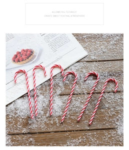 Close-up of red and white striped Christmas candy canes on snowy wood background