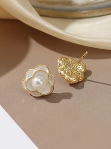 Detail of white camellia stud earrings with pearl centers on silk fabric background