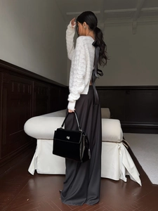 Detail of white hollow-out knit sweater featuring a large black contrast bow on the back