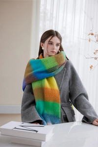 Close-up of soft thick winter scarf featuring colorful plaid patterns and fringe detail