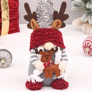 Gnome de Noël avec bonnet à paillettes argentées et bois rouges sur fond de neige