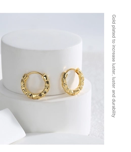 Detail of gold plated brass earrings featuring irregular hammered lava textures