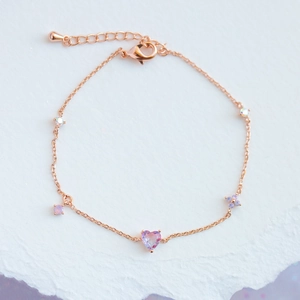 Rose gold chain bracelet with a pink heart zircon and small purple flower charm