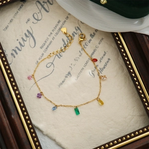 Macro detail of 18K gold-plated bracelet with multi-colored heart and geometric zircons