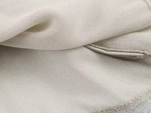 Détail macro du tissu georgette beige clair avec des coutures d'ourlet professionnelles