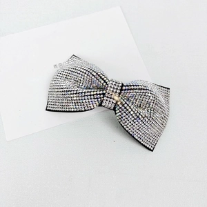 Close-up of sparkling full rhinestone bow hair clip with silver crystals on black base