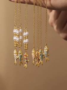 Detail of gold koi fish necklaces with colorful enamel drips and pearl accents