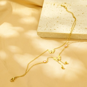 Detail view of double-layer gold necklace with butterfly pendant and pink stones on silk