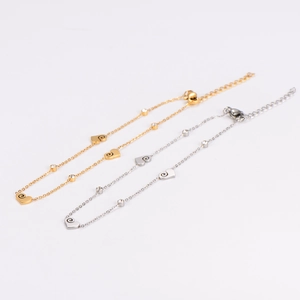Gold and silver heart pendant anklets with spiral patterns and clear stones on white background