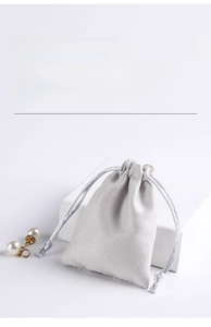 Macro shot of grey sheepskin suede drawstring jewelry pouch on a white display stand