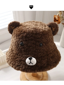 Detail of plush brown teddy bear bucket hat with 3D ears on a wooden stand