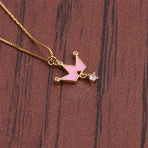 Close-up of golden crown pendant with pink enamel and sparkling zircon gemstones