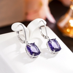 Macro detail of elegant lever-back earrings with rectangular purple gemstones and silver finish