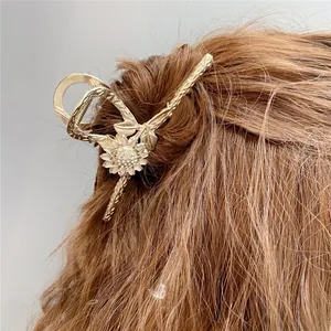 Dettaglio di un fermaglio per capelli a girasole dorato con petali bianchi e strass