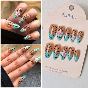 Macro view of leopard print press-on nails with 3D floral accents and gold beads