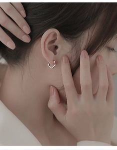 Close-up of minimalist silver hollow flower earrings on model with wavy metal texture