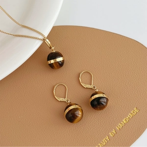 Vintage tiger's eye jewelry set with gold necklace and earrings on leather mat