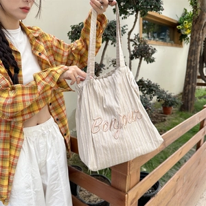 Close-up of striped canvas tote bag with Bonjour embroidery shown in a lifestyle setting