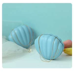 Detail of shell-shaped blue metal wedding favors box with golden chain and pearl pendant
