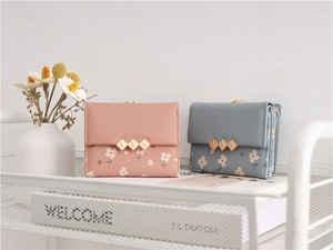 Floral print mini wallets in pink and blue with gold metal buckles on a cozy background