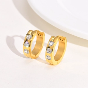 Detail view of gold hoop earrings with three white zircons and snap closure mechanism