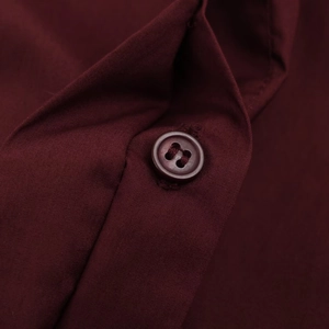 Detailed close-up of dark red poplin fabric texture and matching round button detail