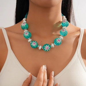 Detail of green melon beads with silver flower accents and pink crystals on necklace