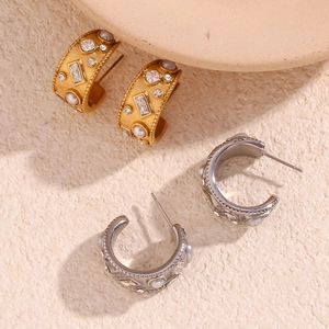 Close-up of gold and silver lava earrings with inset white pearls and zircon stones