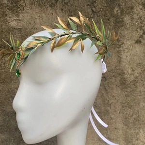Detailed side view of baroque gold leaf headband with green gemstone forehead pendant
