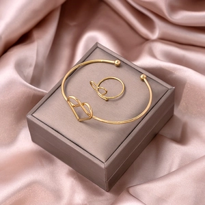 Detailed view of gold hollow heart bracelet and matching ring set on silk background