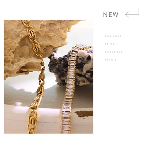 Detail of 18K gold plated chain with rectangular zircon inlay on a stone background