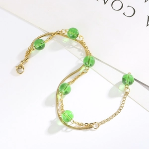 Detailed view of gold double-layer stainless steel bracelet with six green beads