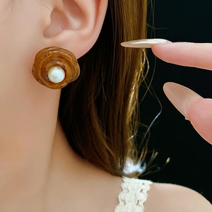Close-up of amber marble swirl earring with a central pearl on a female model