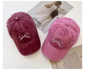 Detail von gewaschenen Baumwoll-Basecaps in Burgund und Rosa mit Schleifenstickerei