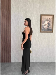 Detail of elegant black one-shoulder dress with ruched texture and slim fit silhouette