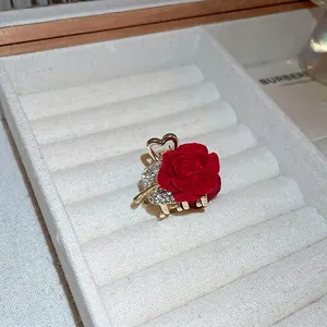 Close-up detail of a red flocked rose hair claw with sparkling rhinestones and golden base