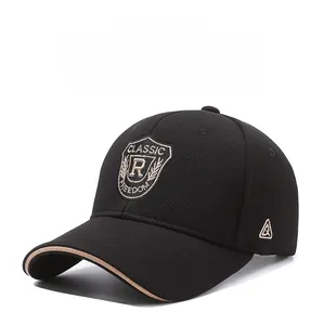 Detail of embroidered shield logo on a black baseball cap with khaki brim piping