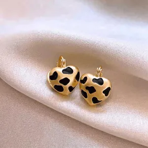 Gros plan de boucles d'oreilles cœur dorées avec motif vache sur fond en soie