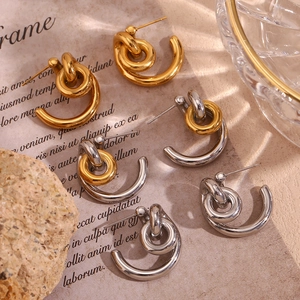 Detailed view of knot-designed hoop earrings in gold and silver finishes on paper background