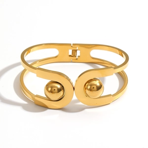 Modern gold stainless steel hinged cuff bracelet with ball details on white background