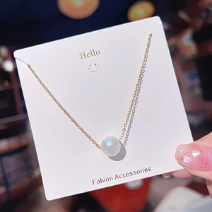Detailed shot of a gold mermaid pearl pendant necklace on a stylish display card
