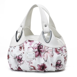 Close-up of floral print handbag featuring white leather handles and silver hardware rivets