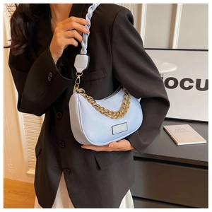 Detail of light blue saddle bag with chunky gold chain and woven shoulder strap