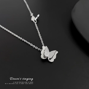Macro detail of silver titanium steel butterfly pendant with dual-layer frosted finish