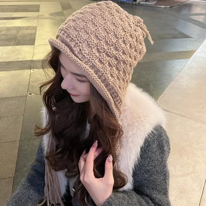 Close-up of khaki knit ear-flap hat with braided tassels and waffle texture detail