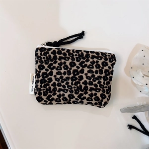 Close-up of leopard print mini pouch with white zipper and side woven brand label