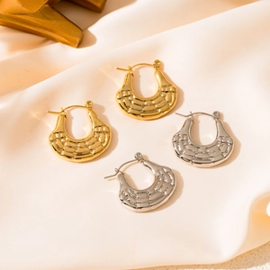 Macro shot of gold and silver U-shaped earrings with textured diamond relief on satin fabric