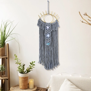 Detail of grey macrame wall hanging with evil eye metal frame and blue crystals